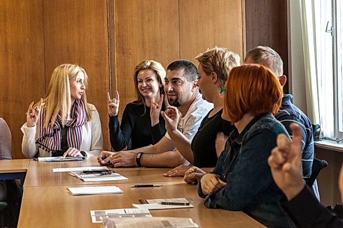 Dziennikarze i fotoreporterzy uczestniczą w warsztatach polskiego języka migowego realizowanych w ramach projektu „Bezpieczni Obywatele Świata Ciszy”. Policjanci prezentują umiejętności zdobyte w trakcie poprzednich zajęć.