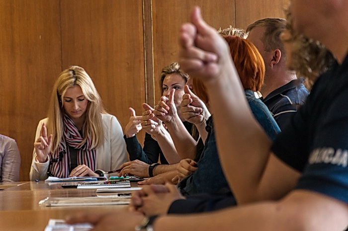 Dziennikarze i fotoreporterzy uczestniczą w warsztatach polskiego języka migowego realizowanych w ramach projektu „Bezpieczni Obywatele Świata Ciszy”. Policjanci prezentują umiejętności zdobyte w trakcie poprzednich zajęć.